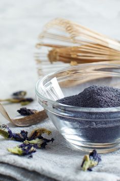 a glass bowl filled with black stuff next to a whisk and spoon on top of a towel