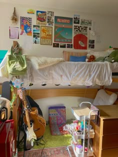 a bedroom with a bed, desk and guitar on the floor in front of it