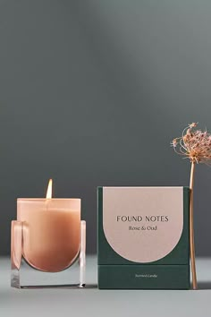 a candle next to a box with a flower in it