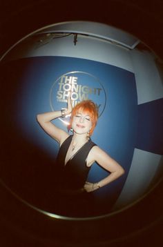 a woman with red hair is posing in front of the tonight show sign and holding her hand on her head