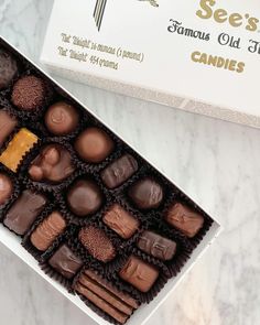 a box of assorted chocolates sitting on a marble counter top next to a card board