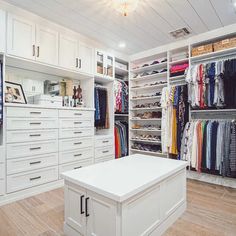 a walk in closet filled with lots of white cabinets and drawers next to a counter