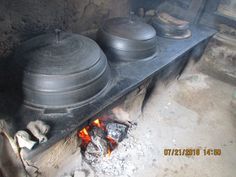 two pots sitting on top of an open fire