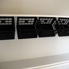 four black baskets are hanging on the wall