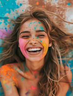 a woman with her hair blowing in the wind and painted all over her face is smiling