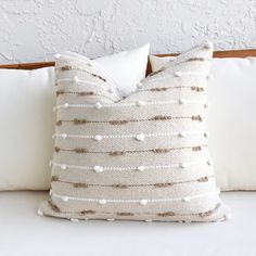 a white and brown pillow sitting on top of a bed