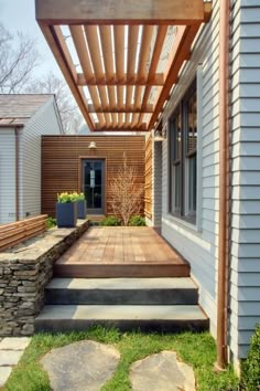 an outdoor patio with stone steps leading to the front door and side entrance, along with a pergolated roof