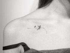 a black and white photo of a woman's shoulder with a small airplane tattoo on it