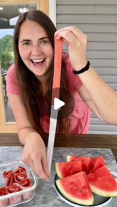 a woman holding a knife over slices of watermelon