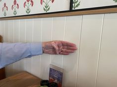 an elderly person's hand reaching for something on the wall in front of them