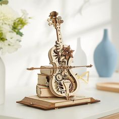 an intricately carved wooden violin sits on top of books in front of a vase with flowers