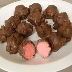 a white plate topped with pieces of chocolate covered in pink and brown frosted candy