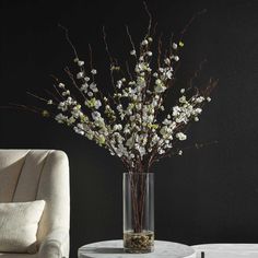 a vase with white flowers sitting on a table next to a chair and ottoman in a room