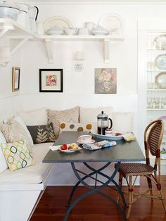 a table with plates and cups on it in front of a white wall filled with dishes