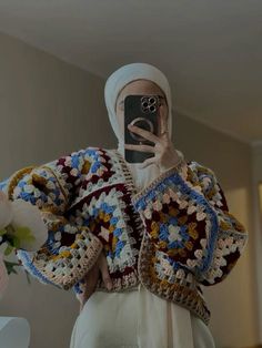 a woman is taking a selfie with her cell phone wearing a crocheted sweater