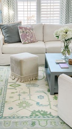 a living room filled with furniture and flowers in vases on top of a coffee table