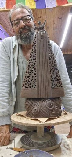 a man is working on a sculpture in his studio with other items around the table