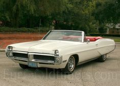 an old white convertible car parked in a parking lot