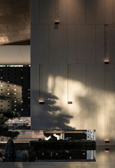 the shadow of a person sitting on a bench in front of a building with lights