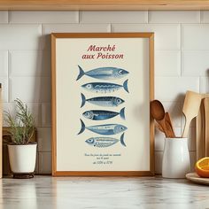 a kitchen counter with a framed poster on the wall next to utensils and an orange