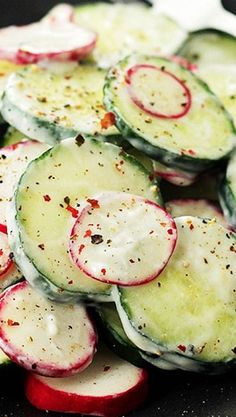 sliced cucumbers and radishes in a pan with seasoning on them