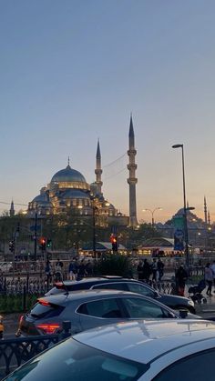 cars are parked in front of the blue mosque at dusk, with people walking by