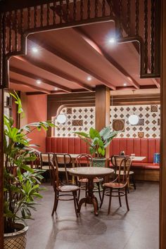 the inside of a restaurant with tables, chairs and potted plants on the table