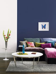 a living room with pink and green walls, white coffee table and colorful couches