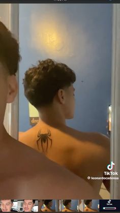 a man with a spider tattoo on his back looking at himself in the bathroom mirror