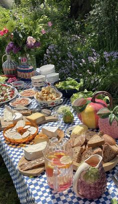 a picnic table with food and drinks on it in the middle of a flower garden