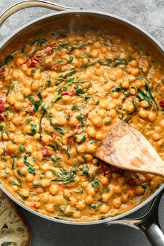 chickpeas and spinach stew in a pan with a wooden spoon on the side