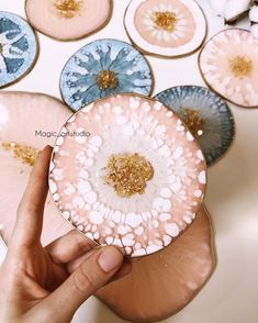 a person holding a plate with flowers on it in front of other plates that have gold and blue designs