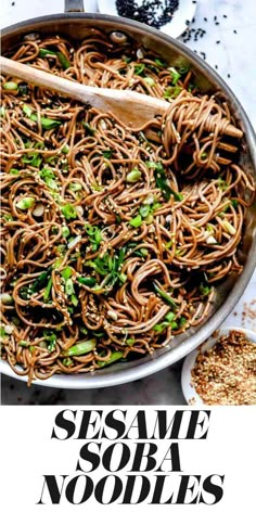 sesame noodle stir fry in a skillet with a wooden spoon on the side