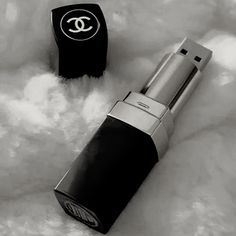 a black and white photo of a chanel lipstick on a fluffy surface next to a lighter