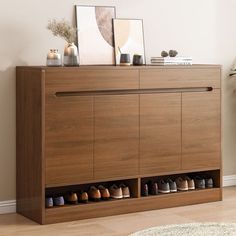 a wooden cabinet with several pairs of shoes on top and two framed pictures above it