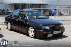 a black car parked in front of a chain link fence