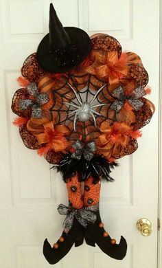 a halloween wreath hanging on the front door with a witch hat and spider web decoration