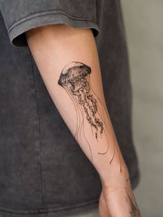 a person with a tattoo on their arm has a jellyfish in it's mouth