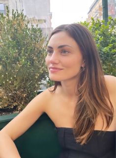 a woman in a black dress sitting on a bench