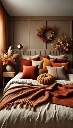 a bed with pillows and blankets on it in a bedroom next to a window filled with pumpkins