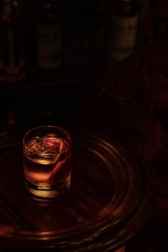 a glass filled with liquid sitting on top of a wooden table