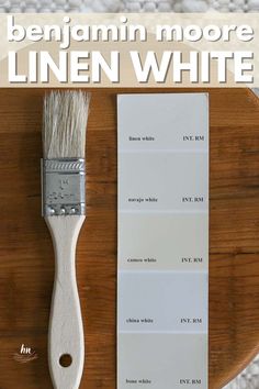 a paint brush sitting on top of a wooden table next to a white color swatch