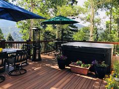 a hot tub sitting on top of a wooden deck next to flowers and an umbrella