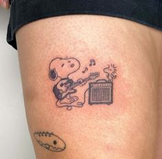 a person with a tattoo on their leg playing the guitar and singing into a radio