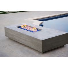 a concrete fire pit sitting on top of a cement floor next to a swimming pool