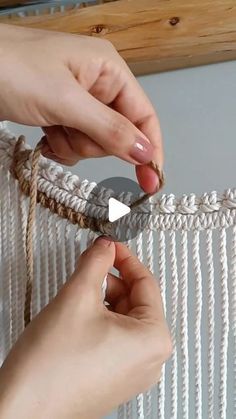 two hands are tying rope to a wall hanging