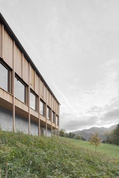 a wooden building sitting on top of a lush green hillside