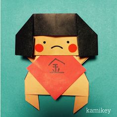 an origami doll with a red bandanna around it's neck and black hair