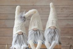 three knitted gnomes sitting on top of a wooden table next to each other