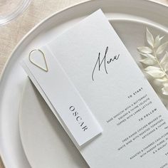 a white plate with a menu on it and a flower in front of the place card